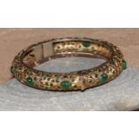 A gilt metal and green stone hinged bangle, possibly Indian, 8cm