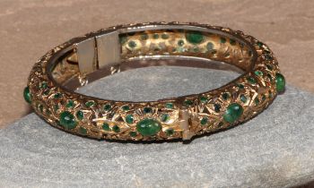 A gilt metal and green stone hinged bangle, possibly Indian, 8cm