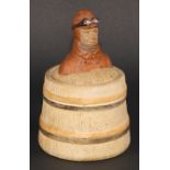 An early 20th century stoneware novelty tobacco jar, the cover with a vintage motorist, bust length,
