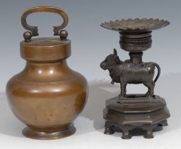 An Indian dark patinated copper alloy bronze temple or shrine lamp, cast as a cow, lotus plateau,