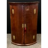 A early 20th century mahogany corner cupboard; cross banded doors with three interior shelves. 103cm