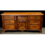A 20th century crossbanded oak low dresser, with an arrangement of seven drawers flanking central