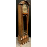 A Gothic Revival oak longcase clock, 30-day musical, chiming movement, brass dial, Roman numerals.