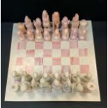 A carved and polished African soap and specimen stone chess set with board.