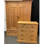 A pine two piece bedroom suite, comprising double wardrobe, with carved roundel detailed corners,