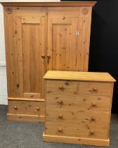 A pine two piece bedroom suite, comprising double wardrobe, with carved roundel detailed corners,