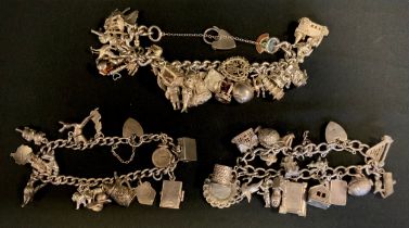 A silver and white metal charm bracelet, suspending twenty six charms, two other bracelets