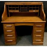 A oak serpentine roll top desk; central drawer to frieze and four graduated drawers to each