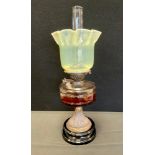 A Victorian oil lamp, with Vaseline yellow/green Uranium glass shade, above clear reservoir and