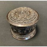 An Anglo-Indian white metal lidded pot, embossed with swirls and flowers, 9cm high