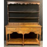 An Elm Welsh dresser, plate-rack top with moulded cornice, shaped apron, three tiers of shelving and