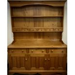 A pine dresser, plate rack top with central row of six spice drawers, over a base with three short