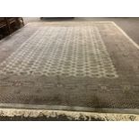 A large middle eastern woolen rug, knotted with abstract motifs in cream and pink on a grey