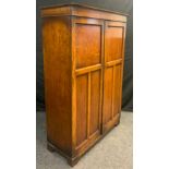 An early 20th century oak Bachelor or Bachelorettes wardrobe, moulded cornice, above pair of