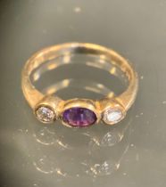 A diamond and amethyst ring, central oval amethyst approx 0.15ct, set between round brilliant cut