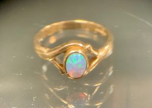 A black opal cabochon ring, approx 0.25ct, with strong green blue and violet colour play, open