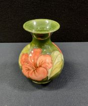 A Moorcroft pottery Hibiscus pattern vase, flared lip, green ground, 13cm high, with Potter to the