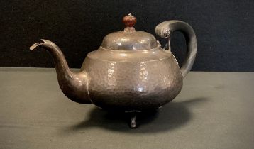 An Arts & Crafts planished silver teapot, ebony handle, tripod feet, retailed by Alexander Clark &