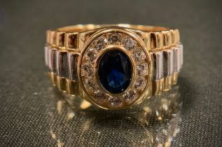 A gold plated silver ring, in the Rolex style set with blue and white cubic zirconia, size P, 7.9g