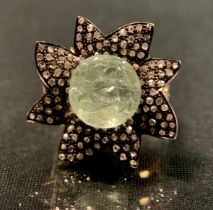 An unusual carved aquamarine and diamond ring, central aquamarine carved as a flowerhead, surrounded