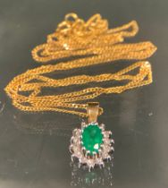 An emerald and diamond pendant necklace, oval green emerald approx 0.25ct, surrounded by fourteen