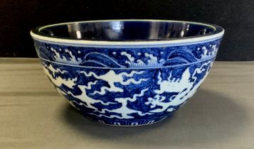 A modern Chinese blue and white bowl, decorated with Dragons amongst clouds,, deep blue and white