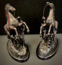 In the manner of Guillaume Coustou the Elder, a pair of cast metal sculptures of man restraining