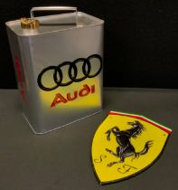 A oil can, embossed Audi in red and black, silver ground, 33cm high.; a cast iron wall shield