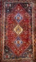 A Persian rug, central row of three geometric medallions, in tones of ocre, blue, red and cream,