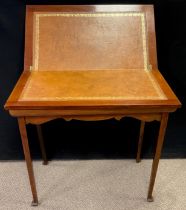 An early 20th century mahogany games table, fold over leather lined top, shaped apron, tapering