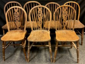 A harlequin set of seven elm spindle-back chairs, comprised of three with wheel splat, and two pairs