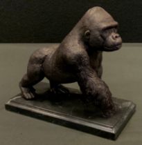 A bronzed metal sculpture of a gorilla, rectangular stepped marble base, 18cm high, 20cm long.