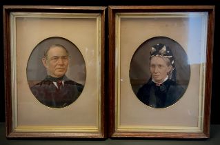 A pair of Victorian over painted photographic panels, Gentleman and lady, oak frames, 29cm x 23cm (