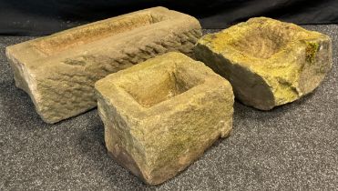 Three rough hewn Derbyshire Gritstone troughs, of graduated sizes, the largest measuring 18 cm