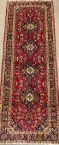 A Central Persian Kashan runner carpet, hand-knotted in rich red, blue, and deep indigo, with