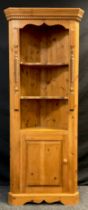 A Pine corner cupboard / shelving unit, dentil cornice above two-tiers of serpentine shaped
