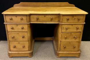 A pine pedestal desk, quarter-galleried top with break-centre shaped front and three drawers to