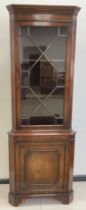 A Georgian style reproduction mahogany corner cabinet, moulded cornice, Astral-glazed door to top,