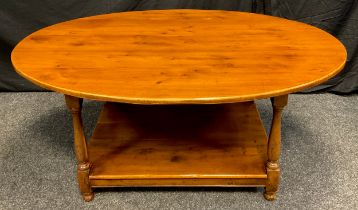 A 20th century oval yew coffee table, shelf under tier, turned supports, 53cm high, 120cm long, 83cm