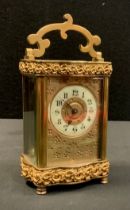 A late 19th century French time piece carriage clock, slight serpentine case with floral banded