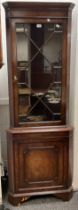 A Georgian style reproduction mahogany corner cabinet, moulded cornice, Astral-glazed door to top,