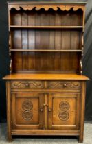 A Titchmarsh and Goodwin style narrow oak dresser, two tiers of shelving to the plate-rack top,