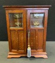 An Edwardian oak smokers cabinet, two door front enclosing fitted interior with four drawers above