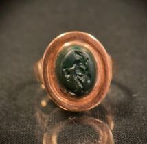 A 19th century intaglio seal ring, carved as a walking figure, unmarked rose metal shank, 5.6g gross