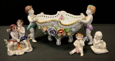 A Continental, Dresden style, boat shaped bowl, as two cherub figures hold the bowl, embossed with