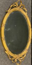 A Victorian oval gilt framed looking glass wall mirror, ribbon swag and cross detailing, 78cm x 47cm