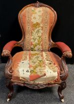 A Victorian carved walnut armchair, stuffed-over back and arms, sprung seat, ornately carved