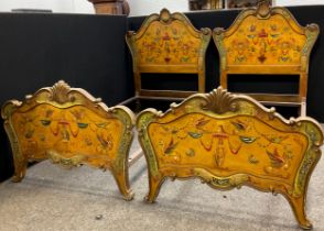 A pair of carved and painted Venetian style single beds, the headboards with carved scallop