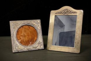 An Elizabeth II silver embossed arche topped rectangular photograph frame, London 1986, another