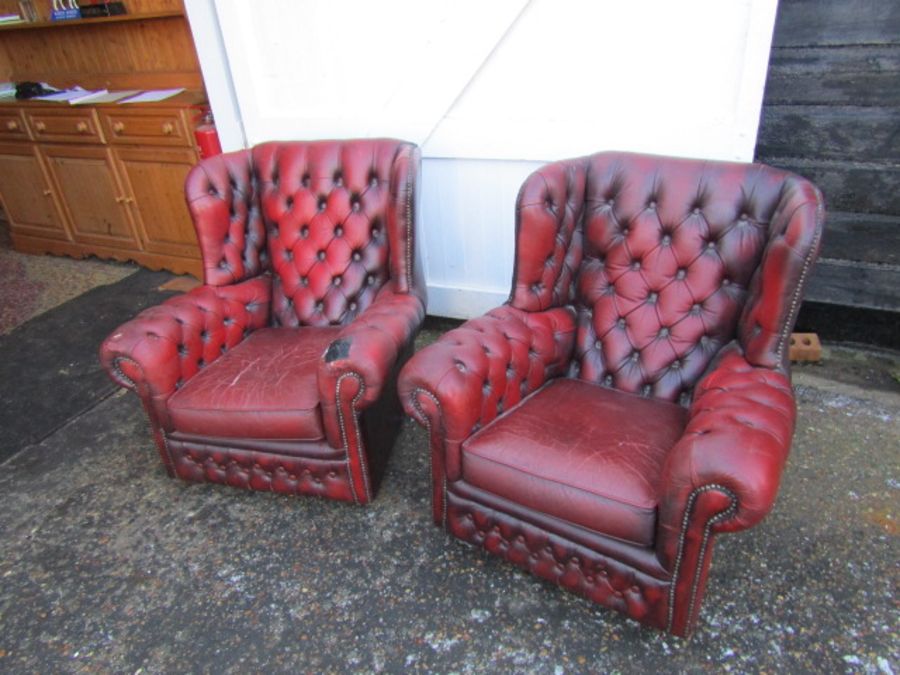 Pair of ox blood red leather button back wing armchairs (some damage to one chair as seen in